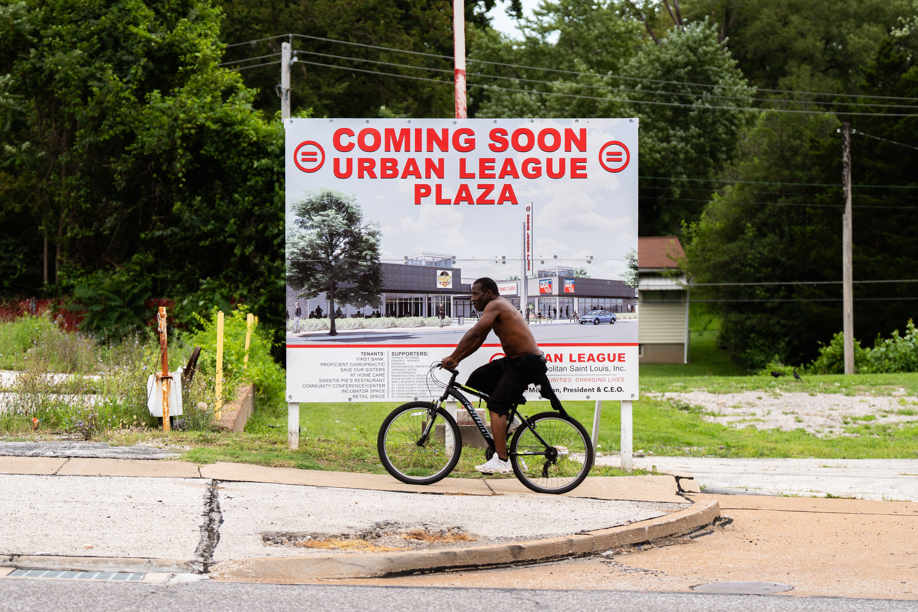 A man rides a bicycle past a sign